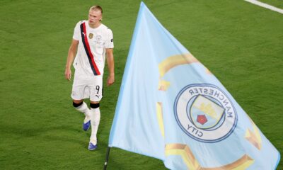 Erling Haaland pictured next to a Man City flag