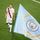 Erling Haaland pictured next to a Man City flag