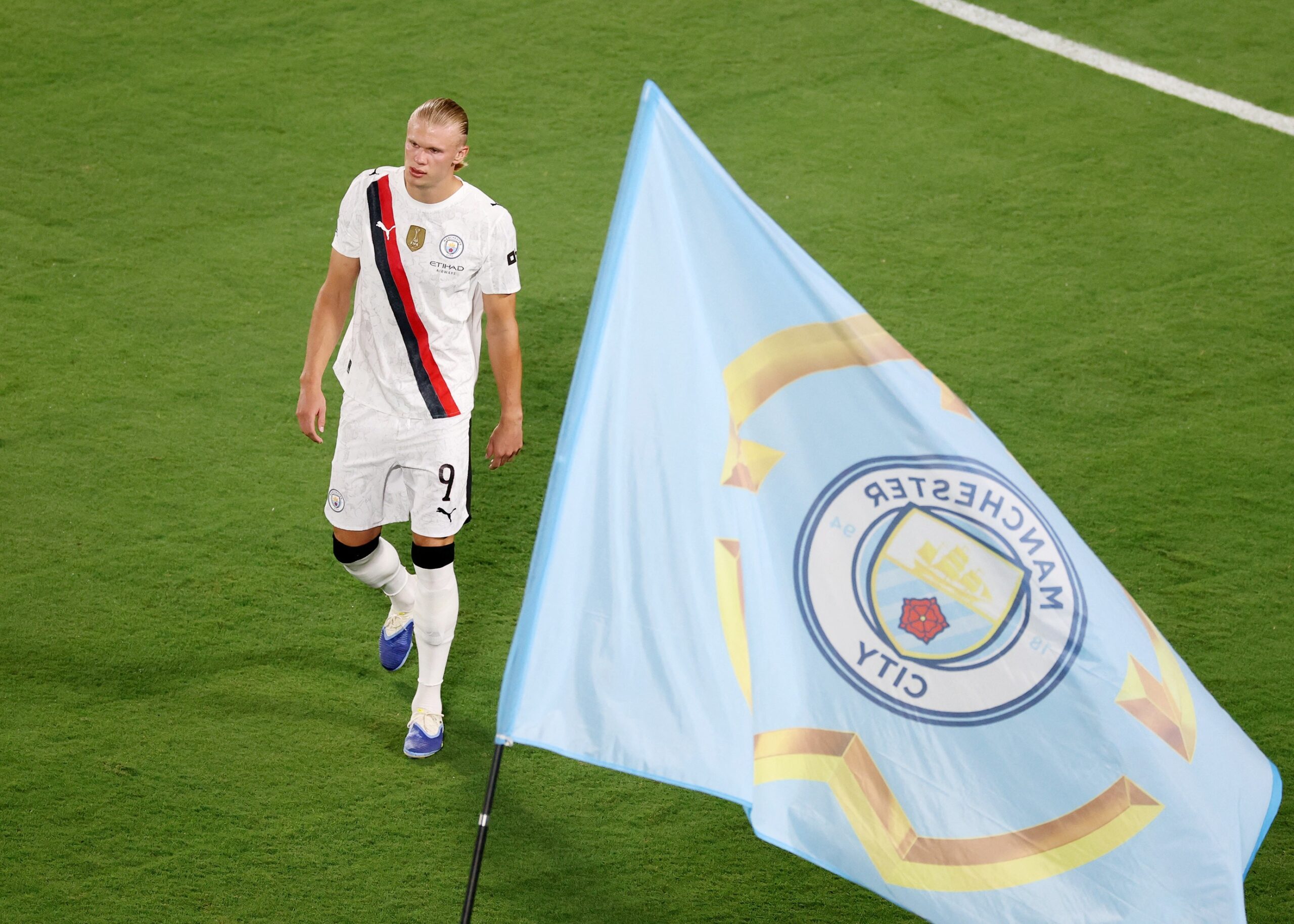 Erling Haaland pictured next to a Man City flag