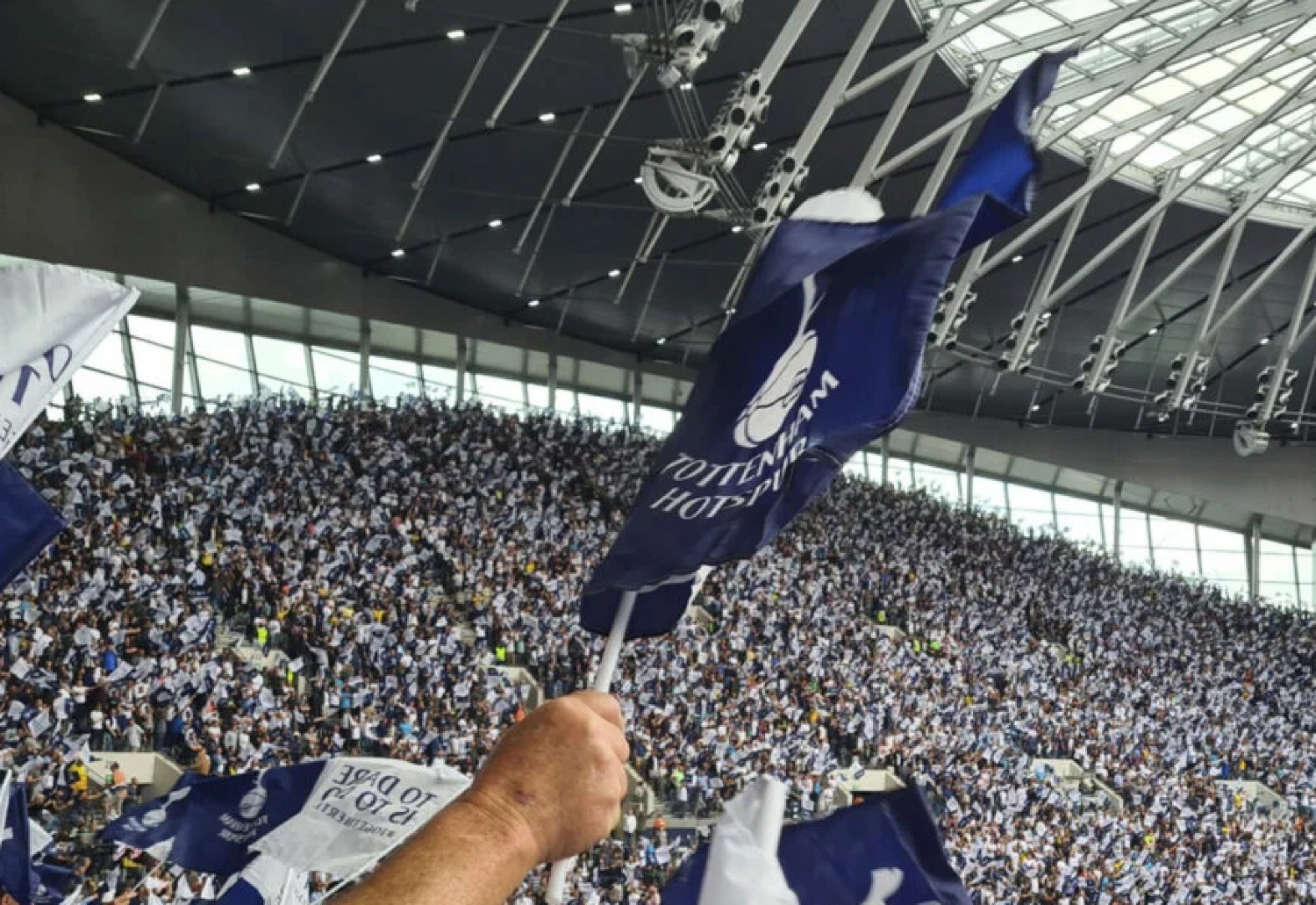 A Tottenham flag pictured waving among a sea of fans