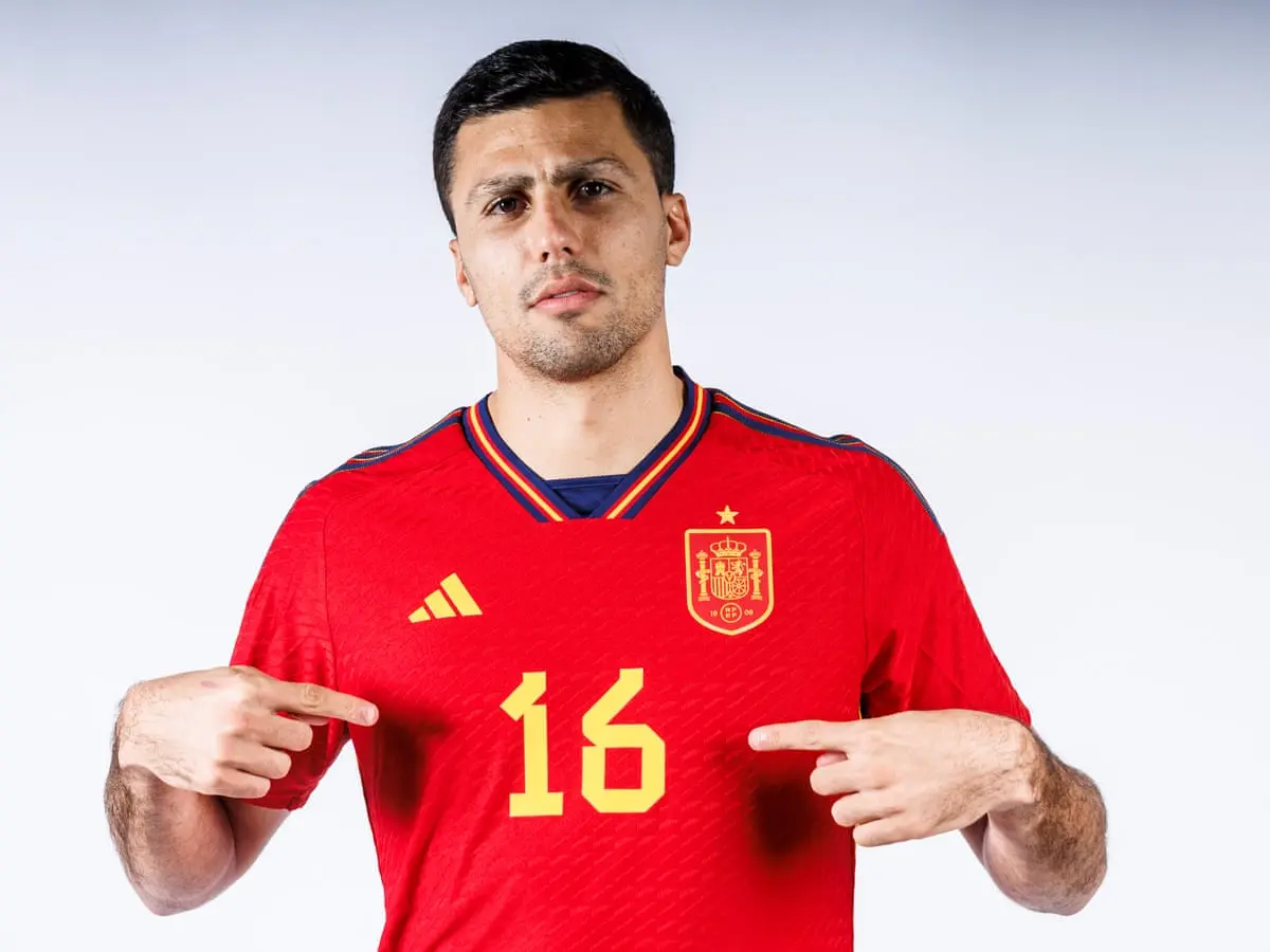 Rodri wearing the Spain national team jersey, pointing to the number 16.