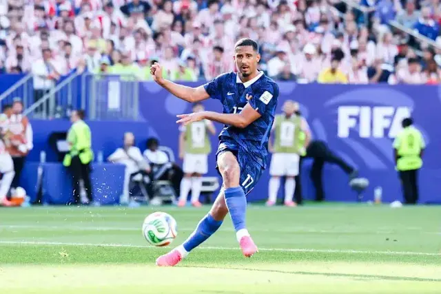 William Saliba kicking a soccer ball during a FIFA World Cup match.